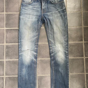 Nudie Jeans Grim Tim 30/32 - Säljer ett par Nudie Jeans Grim Tim i tvätten Rich Blue. Jeansen är i storlek 30/32 med sjukt snygg tvätt och slitningar. Tveka inte vid frågor!!!