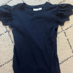 Tröja med volanger - Supersöt mörkblå topp från Gina Tricot med korta volangärmar i broderad spets. Toppen har rund halsringning och är tillverkad i mjuk bomull. Perfekt för dig som vill ha något enkelt men ändå med fina detaljer.