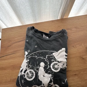 Svart zara t-shirt med E.T tryck - Svart t-shirt med stort vitt tryck från filmen E.T. The Extra-Terrestrial på framsidan. Motivet visar cyklande siluetter framför en måne och stjärnor. Rund halsringning och korta ärmar. Perfekt för filmälskare!