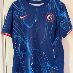 Chelsea FC blå fotbollströja - Chelsea FC matchtröja i blått med abstrakt mönster och röda detaljer. Aldrig andvänd förut. Pris är inte hugget i sten!