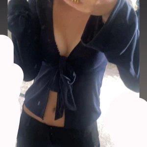 Mörkblå knytblus med v-ringning - Trendig mörkblå blus med djup v-ringning och knyt framtill. Långa ärmar och croppad passform som ger en snygg siluett. Perfekt för dig som vill ha en stilren men ändå chill tröja fråga alltid om ni har nån fundering 🥰 