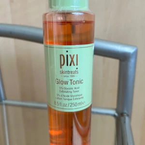 Pixi Glow Tonic 250 ml - Pixi Glow Tonic är en exfolierande toner med 5% glykolsyra som fräschar upp och ger lyster till huden. Passar alla hudtyper och används efter rengöring. Kommer i en genomskinlig plastflaska med grön kork och orange vätska.