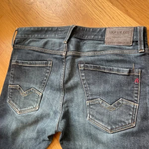 Oanvända Replay Waitom jeans blå denim - Säljer ett par Replay Waitom jeans i klassisk blå denim med snygga slitningar och kontrastsömmar. Jeansen har raka ben. Nypris 1699. Assnygg tvätt 