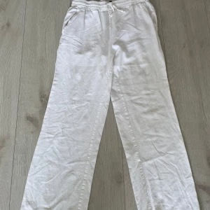 Vita linnebyxor från 157, XS - Luftiga vita linnebyxor från 157 i storlek XS. Byxorna har resår i midjan, raka ben och fickor både fram och bak. Perfekta för varma dagar när du vill ha en chill och stilren look.