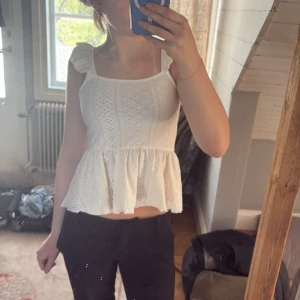 Vit volangtopp med broderade detaljer - Säljer en söt vit topp med volangärmar och broderade detaljer. Toppen har en öppen rygg med snören! Använd endast några gånger!  