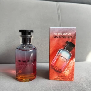 Louis Vuitton On The Beach parfym 100ml - Exklusiv parfym från Louis Vuitton, On The Beach, i en snygg glasflaska med färgskiftning från blått till orange och svart lock med LV-logga. Kommer i originalkartong med matchande färger och tydlig branding. Flaskan rymmer 100 ml Eau de Parfum. Har endast använd några sprut, och jag säljer den eftersom att jag tycker att den är lite för femenim för min smak:)