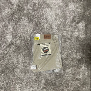 Beige Lee Daren Zip Fly byxor W34/L32 - Säljer ett par snygga beige Lee Daren Zip Fly byxor i regular straight fit. Byxorna är tillverkade i slitstark bomullstwill och har klassisk Lee-lapp bak i midjan. Perfekta för dig som gillar en clean och tidlös look.