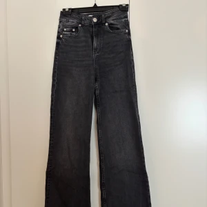 Svarta wide jeans från Gina - Snygga svarta jeans från Gina tricot med hög midja och breda ben. Jeansen har klassisk femficksdesign, silverfärgade knappar och dragkedja. Materialet är denim i bomull och passformen är loose och trendig. Perfekta för dig som gillar en avslappnad och cool stil.