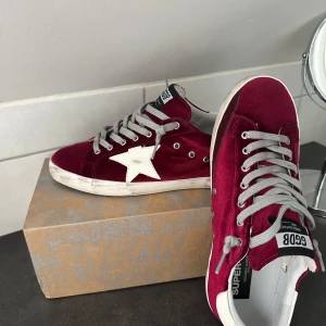 Super star - Vinröda sneakers från Golden Goose modell super star, sorlek 43 eller uk9. Använda endast en gång av mig annars är de i nyskick. Skorna är köpta på Vestiaire collective, kvitto finns och kartong.