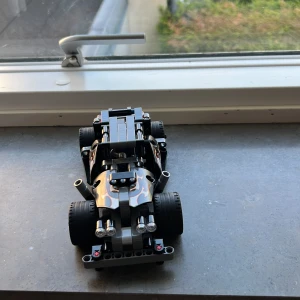 Bygd legobil billigt - Bilderna visar en cool LEGO Technic-bil med svarta och guldiga detaljer, eldflammor och dödskalledekor på sidorna. Perfekt för dig som gillar att bygga och köra häftiga bilar! Passar både som samlarobjekt och för lek.