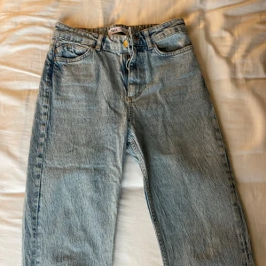 Ljusblå raka jeans från Zara - Ljusblå jeans från Zara med klassisk femficksdesign och raka ben. Jeansen har hög midja, bälteshällor och stängs med dragkedja och knapp. Tillverkade i robust denim som ger en tidlös look. Perfekta för dig som gillar en avslappnad och stilren vibe.