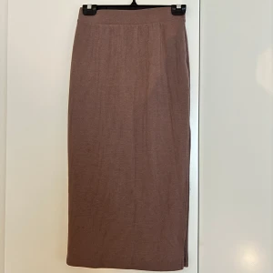 Brun ribbad långkjol från Vero Moda - Säljer en brun ribbad långkjol från Vero Moda i storlek XS. Kjolen har en rak passform och en snygg slits på sidan som ger extra edge. Perfekt att styla med chunky sneakers eller boots för en chill look.