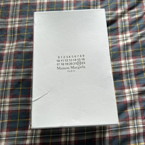 Maison Margiela gats - Maison Margiela gats sneakers i helsvart med både mocka och skinnpaneler. Klassisk siluett med rund tå, svarta snören och svart sula. Insidan är ljusbeige och skon har diskreta detaljer som gör dem riktigt stilrena och unika.
