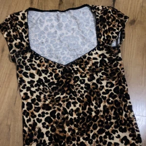 Leopardmönstrad kort klänning - Snygg kort klänning med leopardmönster och v-ringning. Klänningen har korta ärmar och är i mjukt, stretchigt material. Perfekt för dig som vill sticka ut med ett djurmönster och cool vibe.