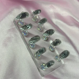 SilverSpell (XS);Medium Almond - Snygga handgjorda gelé press-on naglar i svart med unika silverdetaljer och 3D-mönster. Kommer i storlek  XS: 14 mm, 11 mm, 11,5 mm, 10 mm, 8 mm . Perfekt för dig som vill ha en edgy look utan att gå till salong.