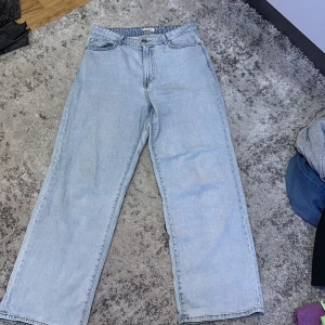 Ljusblå raka jeans från Lindex - Ljusblå jeans från Lindex i rak modell med klassiska fem fickor och normal passform. Jeansen har hög midja och är tillverkade i bomullsdenim. Perfekta för en avslappnad och trendig look.