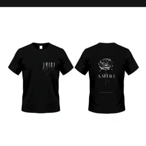 Svart AMIRI t-shirt med tryck - Svart t-shirt från AMIRI med coolt tryck framtill och en stor ros med logga på ryggen. Klassisk passform och rund halsringning. Perfekt för dig som gillar streetstyle och vill sticka ut med snygga detaljer.