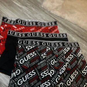 3-pack GUESS boxers med logga S - Säljer ett 3-pack kalsonger  från GUESS i storlek S. Två par har svart och röd logotypmönster, ett par är helsvart med logotyp i midjan. Sköna och stretchiga i bomull och elastan, perfekt för dig som gillar snygga underkläder med tydlig branding. helt nya! Aldrig använda såklart