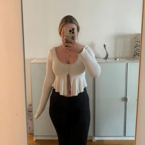 Vit croppad långärmad topp - Säljer nu denna söta toppen från Gina tricot! Supersöt vit croppad topp med lång ärm och volangkant nertill. Toppen har en liten knytning framtill och spetsdetaljer längs urringningen. Toppen är i storlek S och använd ett fåtal gånger🩷 Hör av er vid frågor eller fler bilder 