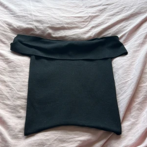 Svart offshoulder tubtopp från Zara - Svart tubtopp från Zara med offshoulder-design och bred volangkant upptill. Snygg och enkel modell som sitter tight och är perfekt att styla med jeans eller kjol. Mjuk och stretchig känsla.