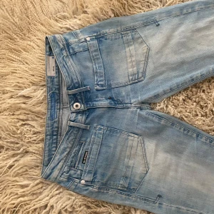 Ljusblå lågmidjade jeans från G-Star RAW - Säljer ett par ljusblå lågmidjade jeans från G-Star RAW med vintage look och skinny passform. Jeansen har unika fickor och slitsar, de är perfekta att ha som de är eller sy om till bootcut❤️