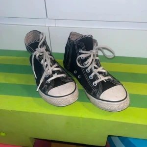 Svarta sneakers från Mywear, strl 32 - Klassiska svarta sneakers från Mywear i storlek 32. Skorna har vit sula, vita snören och kontrasterande vita sömmar. Rund tå och platt sula ger en tidlös look. Perfekta för dig som gillar enkel och stilren streetstil.