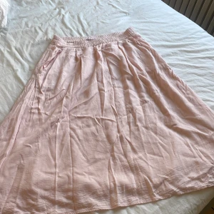 Ljusrosa kjol från 157 - Säljer en söt ljusrosa kjol från 157 i storlek XS. Kjolen har en elastisk midja för extra komfort och är perfekt för varma dagar. Man kan ha den högmidjat och låg midjat, tjolen går ned vid knäna så om man vill kan man ju sy om kjolen till något nytt. 