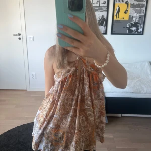 Söt mönstrad sommartopp - Söt mönstrad sommartopp som är halterneck i en orange/beige ton! Jättefin nu till vår och sommar!🧡🧡 OBS. Axelbanden går att justera. Några få defekter som man inte tänker på, skriv privat för bilder!