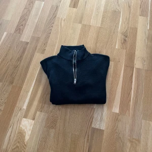 Svart tröja med dragkedja - Snygg svart tröja med dragkedja i halsen. Perfekt för en stilren look. Passar bra till både jeans och chinos.