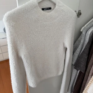 Vit fluffig tröja från Gina Tricot - Mysig vit tröja från Gina Tricot med en fluffig textur. Tröjan har långa ärmar och en rund halsringning, perfekt för kyligare dagar. Den är både stilren och bekväm, vilket gör den till ett mångsidigt tillskott i garderoben.