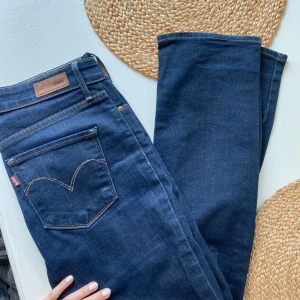 Mörkblå jeans från Levi's - Snygga mörkblå jeans från Levi's med en klassisk straight fit. De har en midwaist passform och är perfekta för en avslappnad stil. Levi's ikoniska logga syns på bakfickan.