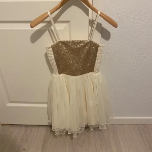 Glittrig klänning från Lindex - Säljer en söt klänning från Lindex med glittrig överdel och volangkjol i ljus färg. Klänningen har smala axelband och är perfekt för festliga tillfällen. Den glittriga delen ger en extra touch av glamour.