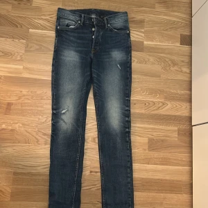 Blå jeans med hål, slim fit - Snygga blå jeans med slitningar och en klassisk femficksdesign. De har en knappgylf och en lätt tvättad look som ger en avslappnad stil. Perfekta för en casual outfit. Helt oanvända. 