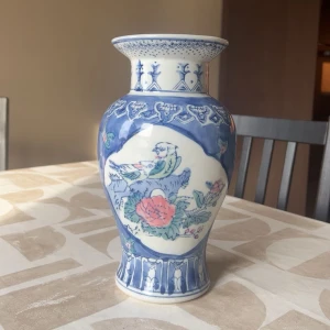 Blåvit vas med fågel- och blommotiv - Vacker blåvit vas med detaljerade motiv av fåglar och blommor. Vasen har en elegant form med en bred öppning och dekorativa mönster runt om. Perfekt som en stilfull inredningsdetalj.