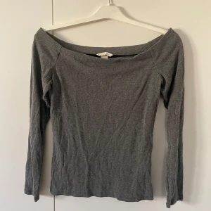Offshoulder tröja - Fin grå ribbad, tight offshoulder topp med långa ärmar. Perfekt för en stilren look. Passar bra till både jeans och kjol.