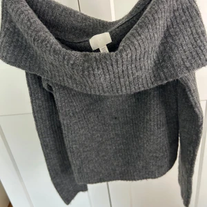 Grå stickad tröja från H&M - Säljer en grå stickad tröja från H&M med en bred krage då den är för liten för mig. Tröjan har bra kvalitet och är använd ett fåtals gånger!