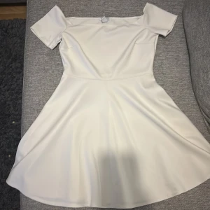Vit offshoulder klänning NLY One S - Sänkt pris pga fläcken, ni får tvätta bort. Superfin vit kortklänning från NLY One i offshoulder-modell. Klänningen har korta ärmar och en utsvängd kjol som ger en snygg siluett. Materialet är slätt och känns mjukt mot huden, perfekt för sommarens alla tillfällen.