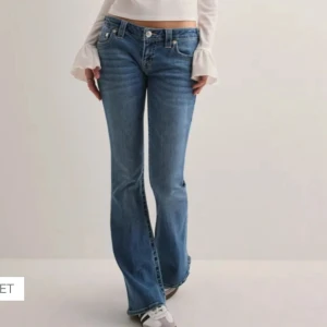 True Religion blå bootcut jeans - Snygga blå jeans från True Religion med bootcut passform och låg midja. Klassiska kontrastsömmar och ikoniska bakfickor med broderad logga. Köpt för 1400 men kan säljas för 1000!!❤️❤️ De är proffesionellt uppsydda då de var för långa, passar någon mellan 160-168 skulle jag säga❤️ ALDRIG ANVÄNDA!!