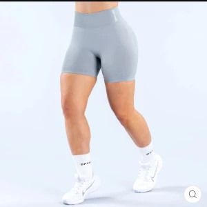 Ljusgrå träningstights-shorts från Dryne - Supersnygga ljusgrå träningstights-shorts från Dryne med hög midja och tight passform. Perfekta för gymmet eller löprundan, tillverkade i stretchigt syntetmaterial som andas. Diskret logga på linningen och stilren design som sitter på plats under hela passet. Dynamic Shorts. Använda 1 gång
