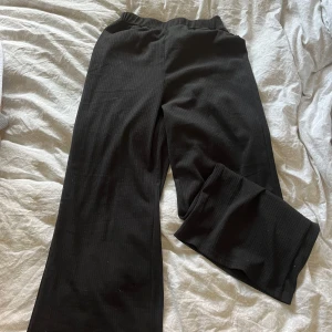 Svarta ribbade byxor från SHEIN - Svarta ribbade byxor från SHEIN med elastisk midja och raka, vida ben. Mjukt och stretchigt material som är riktigt skönt att ha på sig. Perfekta för en chill och avslappnad stil.