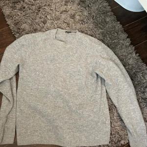 Grå kashmir/merinoull tröja - Mysig grå stickad tröja från Uniqlo i storlek M. Tröjan har en klassisk rund halsringning och långa ärmar. Perfekt för lager-på-lager och enkel att matcha med jeans eller kjol. Materialet är mjukt och ger en chill vibe.
