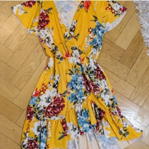 Gul blommig kortklänning Gina Tricot XS - Superfin, söt gul kortklänning från Gina Tricot med färgglatt blommönster i rött, blått och vitt. Klänningen har v-ringning, volangkant nertill och korta ärmar. Tillverkad i mjuk polyesterblandning med elastan för extra komfort. Perfekt för sommarens alla tillfällen!