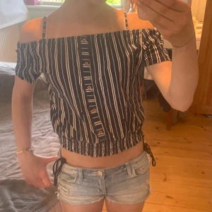 Randig offshoulder topp med knappar - Snygg croppad offshoulder topp med marinblå och vita ränder. Super söt till sommaren. Passar mellan storlekarna xxs och xs