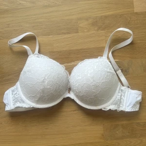 Vit push up bh från Lindex model Linnea  - Säljer en vit push up bh från Lindex i model Linnea i storlek 75B. Bh:n har vadderade kupor och är täckt med spets på utsidan. Axelbanden är justerbara, andvänd ett fåtal gånger 