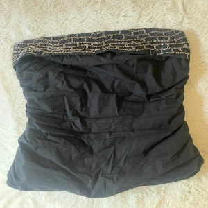 Svart tubtopp med glitter från Zara - Snygg svart tubtopp från Zara med glittriga pärldetaljer upptill. Toppen är bandeau-modell och har en tight passform som sitter på plats. Skriv privat för bild med toppen på. Köpt för 250.