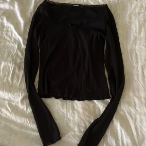 Svart långärmad topp med spets från BikBok - en svart tunn tröja i ribbat material och spets runt urringningen, använd flera gånger och har någon tråd lös (se på sista bilden) 💕skriv vid frågor!