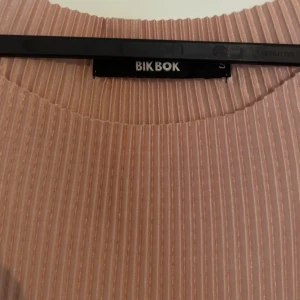 Lång ribbad klänning från Bik Bok - Säljer en lång, ribbad klänning från Bik Bok i en ljus beige ton. Klänningen är ärmlös och har en rak, slim passform med rund halsringning. Perfekt för dig som gillar stilrena och enkla plagg med en modern touch, väldigt söt🌸