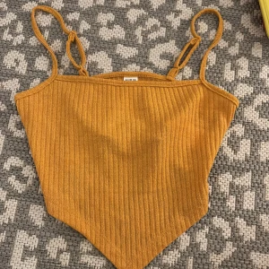 Gul ribbad linnetopp från SHEIN - Snygg gul ribbad linnetopp från SHEIN med smala axelband. Toppen har en spetsig nederkant och är croppa, perfekt till jeans eller kjol. Materialet är mjukt och stretchigt, vilket gör den superbekväm att bära.