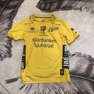 Gul Elfsborg matchtröja Umbro nr 26 - Elfsborgs officiella matchtröja i starkt gul färg med svarta detaljer och tryck, tillverkad i lätt och ventilerande polyester. Nummer 26 och namnet Pulsen på ryggen, flera sponsorloggor och klubbmärke framtill. Klassisk krage och korta ärmar. (Är från en fotbollspelare)