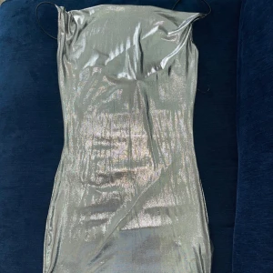 Glittrig silver klänning - Supersnygg glittrig silverfärgad kortklänning från H&M Divided. Klänningen har tunna axelband och en tight passform som framhäver figuren. Perfekt för dig som vill sticka ut med metallic-vibe och trendig look. Materialet är mjukt och följsamt syntet. Prislapp på